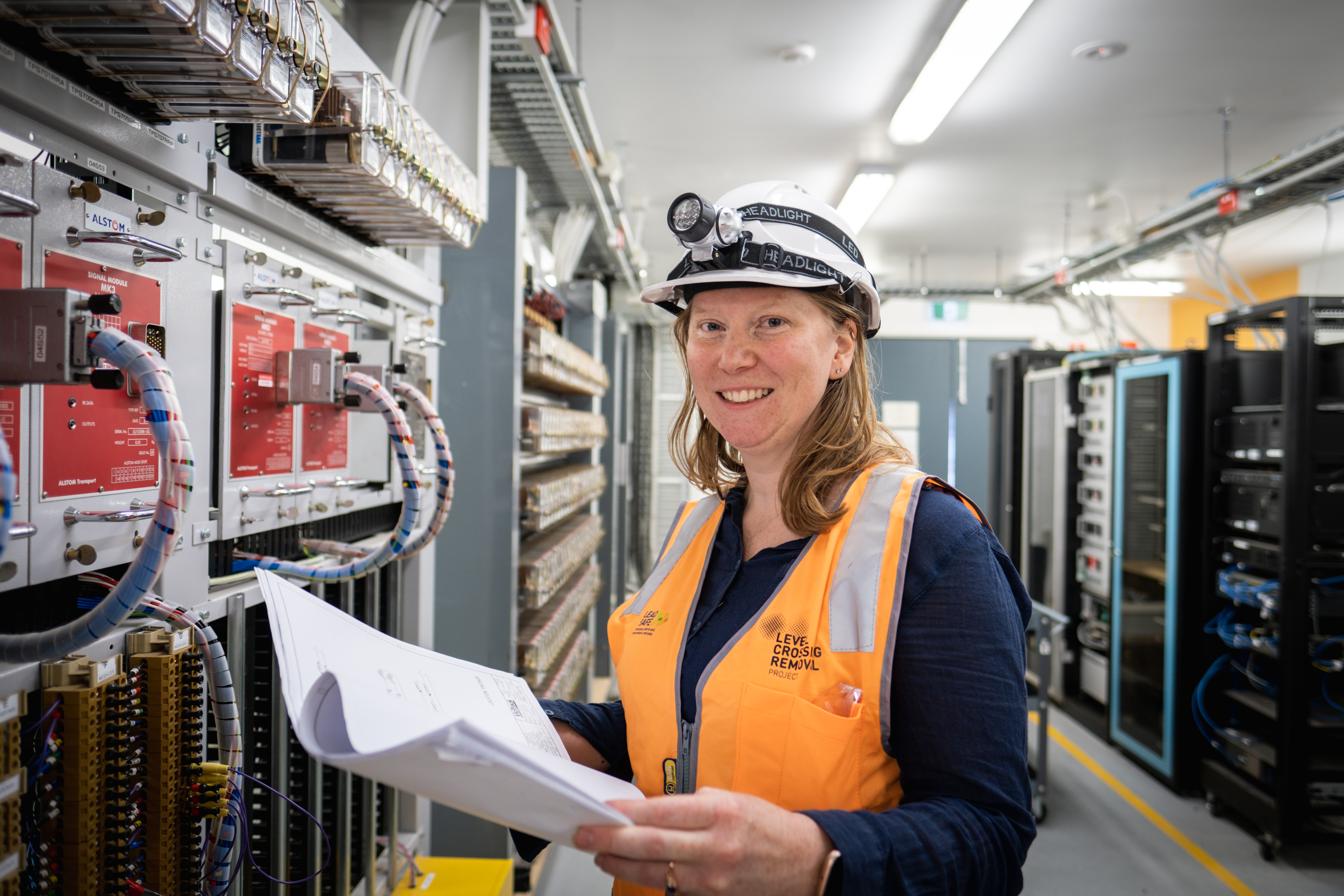 Female electrical worker looking at plans in front of electrical circuit