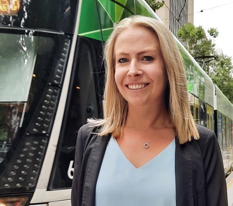 Woman in suit standing in font of tram