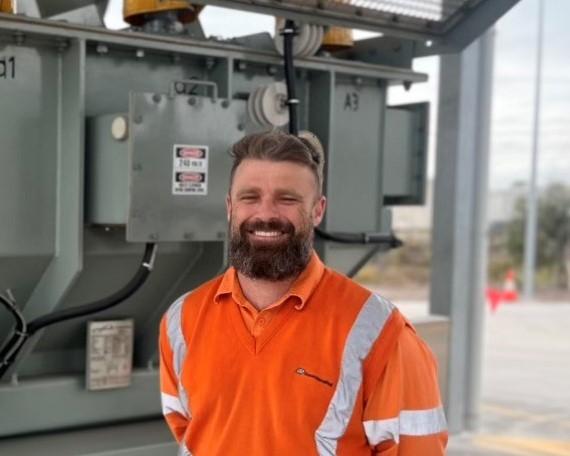 Rail electrician standing in front of substation.