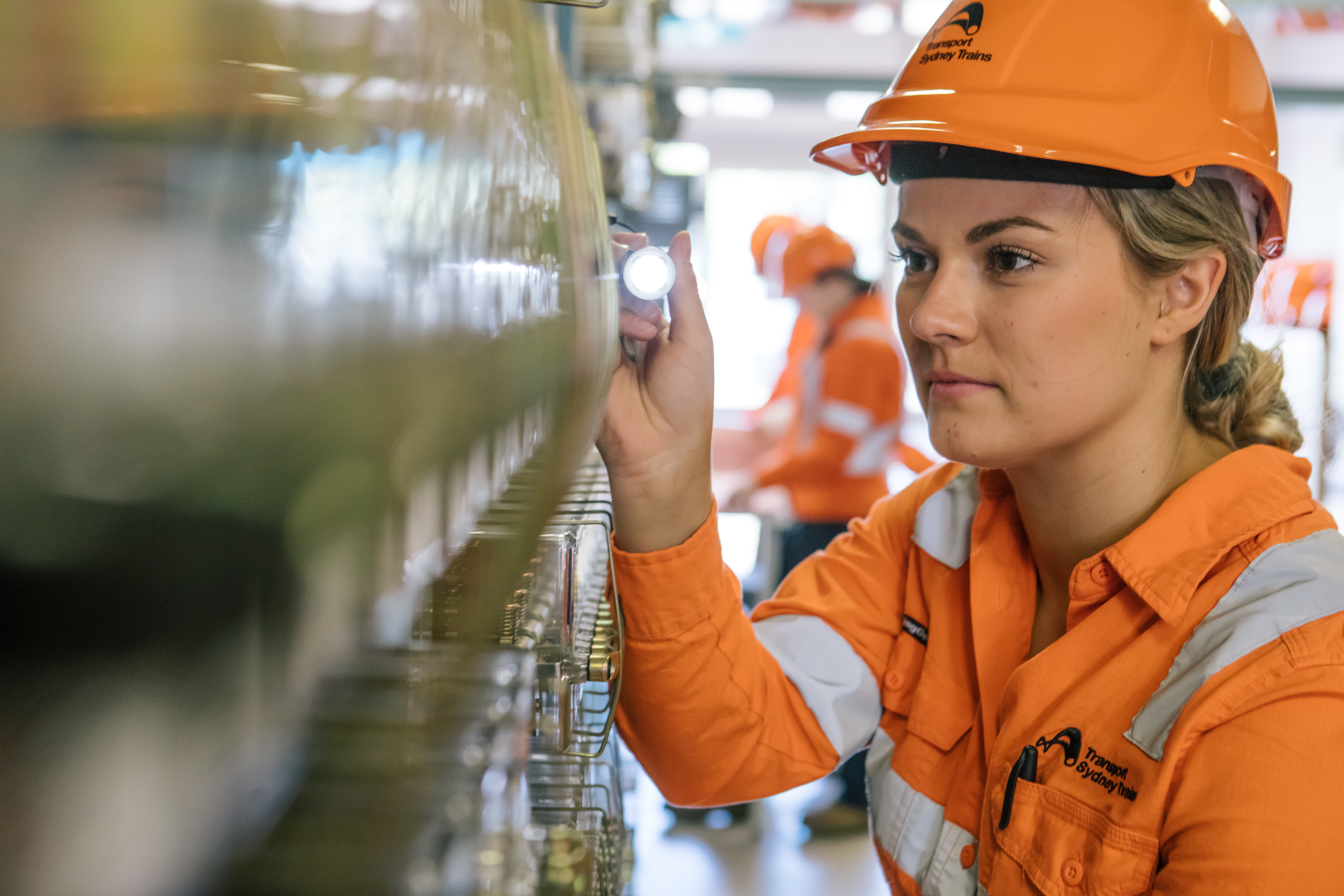 Female rail Signalling Technician testing circuits on a signalling power board