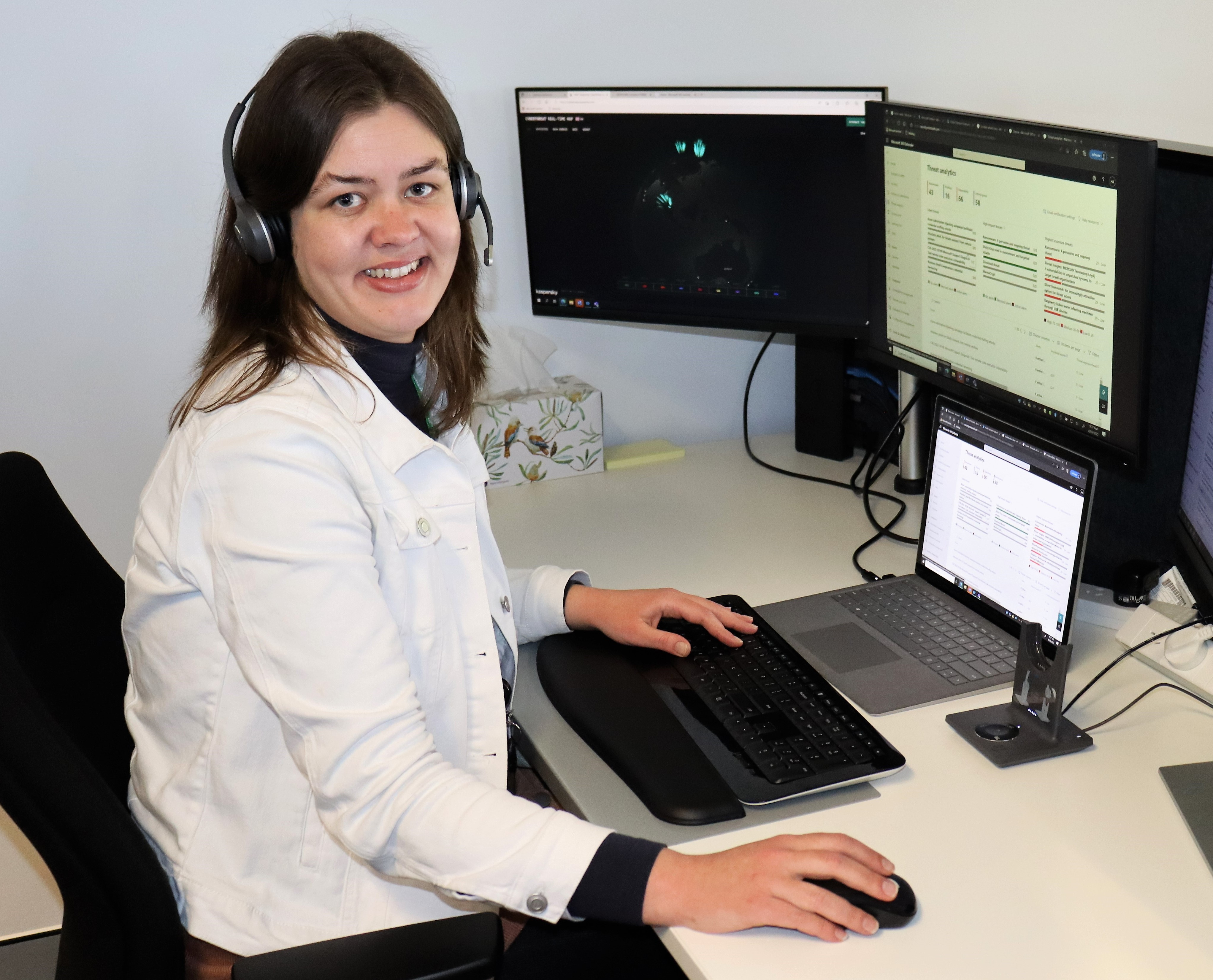 Female ICT security specialist sitting in front of computer screens.