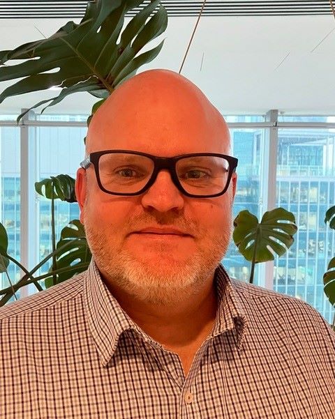 A man in glasses standing in an office.