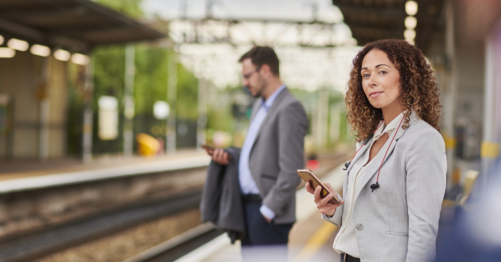 Professional woman with phone standing on rail platform.