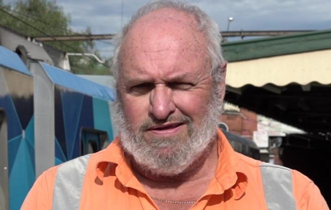 Close up photo of male Sterling Infrastructure worker standing by train at a suburban station.