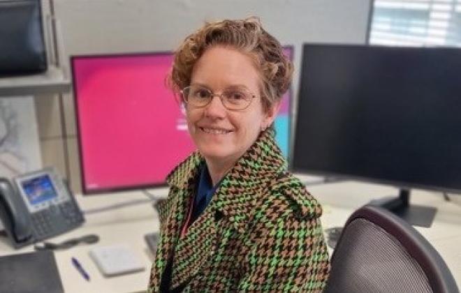 Woman sitting at desk in front of computers