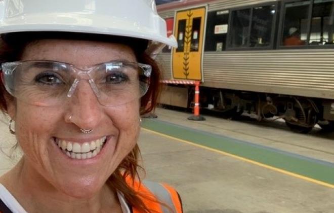 Woman in hard hat standing in front of train on rail platform