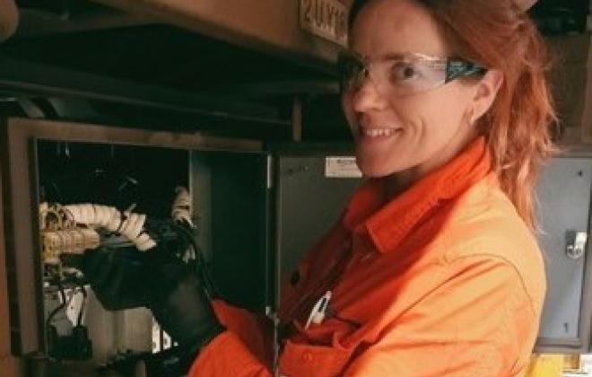 Woman in high visibility clothing fixing electrical unit