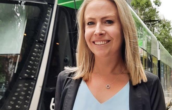 Woman in suit standing in font of tram