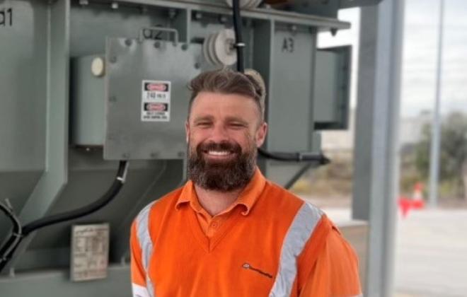 Rail electrician standing in front of substation.