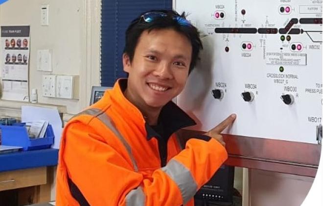 Man wearing high visibility clothing pointing at rail systems map.