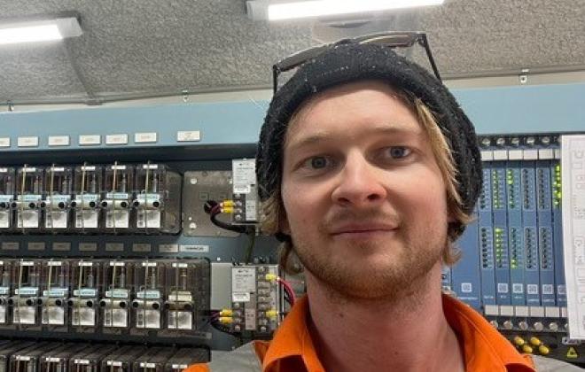 Male signalling technician standing in front of electrical unit