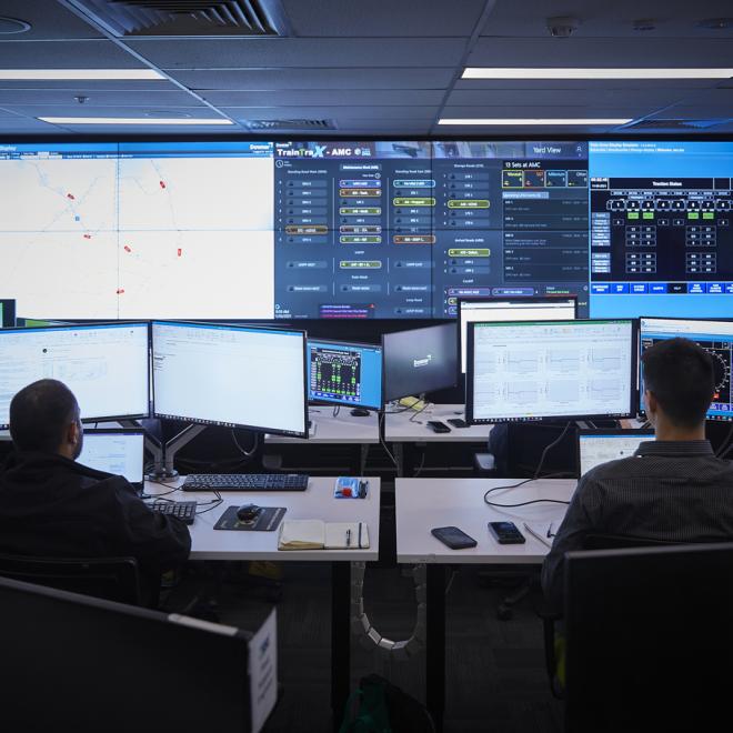 Two workers in front of screens in a network control room.